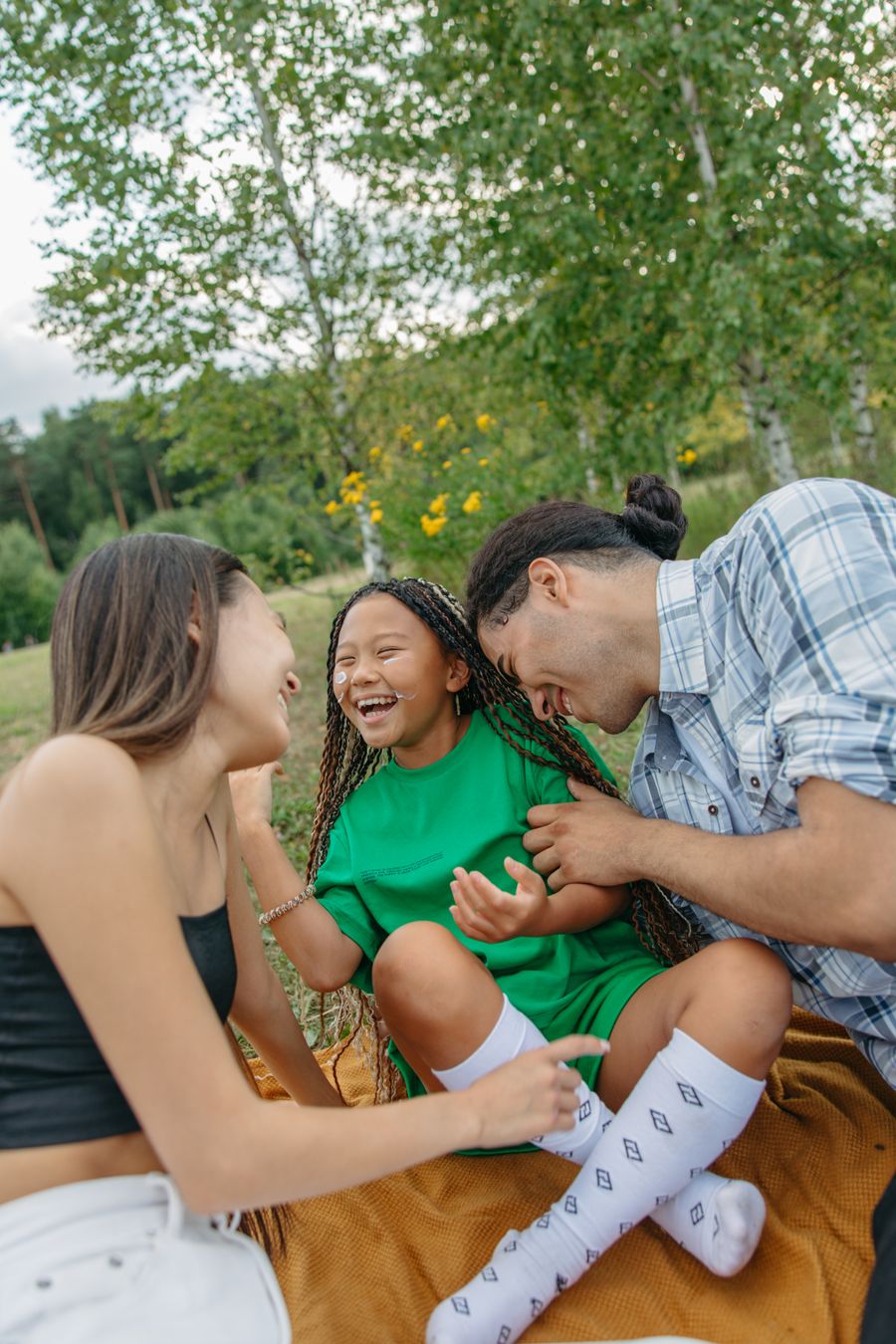 Parents tickling their daughter on a picnic